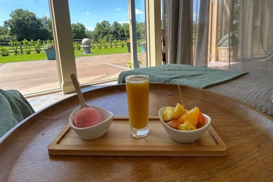 A breakfast tray of fresh juice, fruit and sorbet by the window at Revas Spa